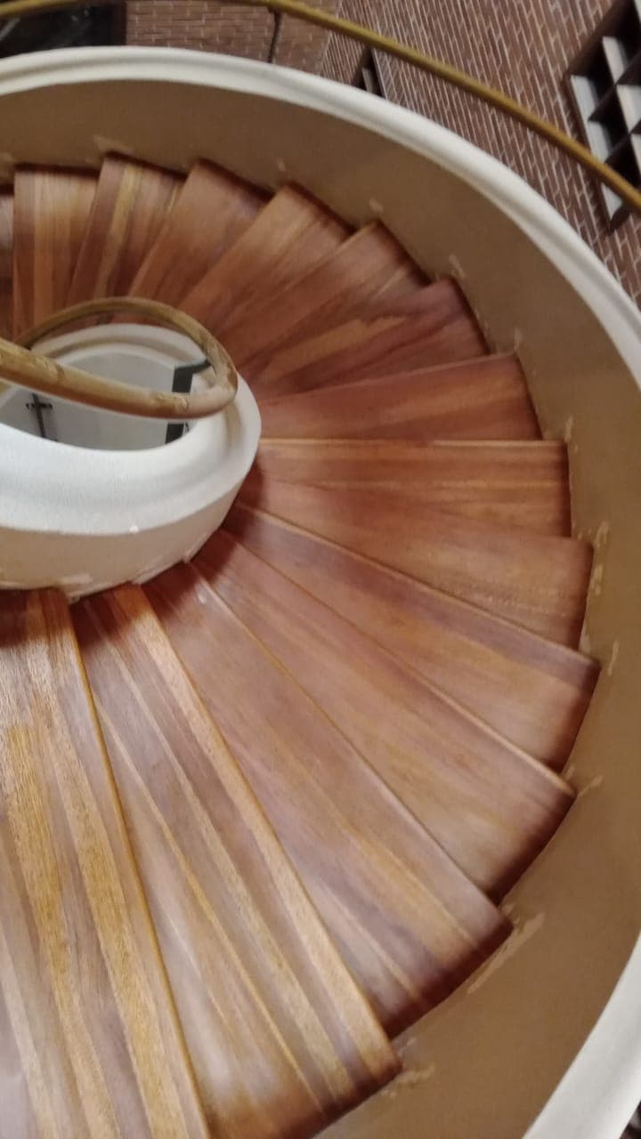 Vista cenital de escalera caracol en madera rojiza — detalle de peldaños